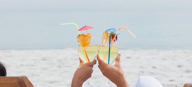 Couple clinking glasses of cocktail on beach