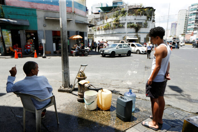 FOTO DE ARCHIVO. La gente llena recipientes de plástico con agua de una boca contra incendios durante el día Mundial del Agua, en Caracas, Venezuela Servicios deficientes, sin subsidios y con aumento de tarifas