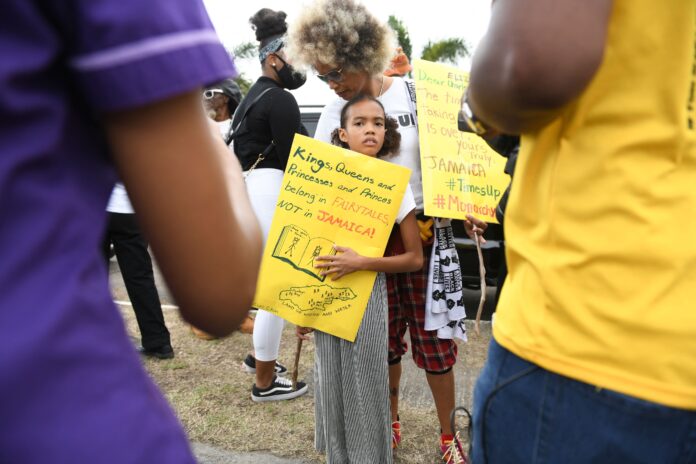 Una niña jamaiquina sostiene un cartel que dice 